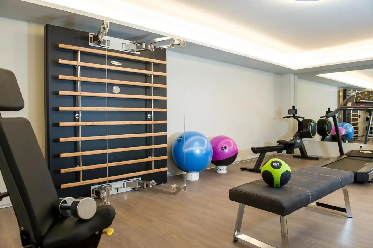 Moderner Fitnessraum mit Sprossenwand, Hantelbank und Cardiogeräten im Hotel Post Velden