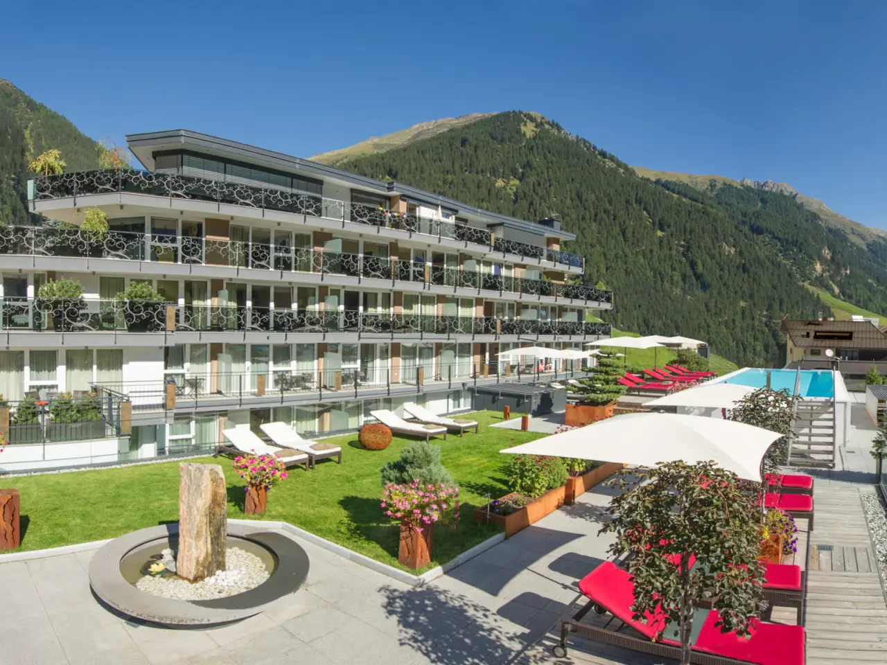 Hotel Fliana Aussenansicht mit Pool, Sonnenterrasse, Liegewiese und Alpenpanorama. Ideal für Wellnessurlaub.