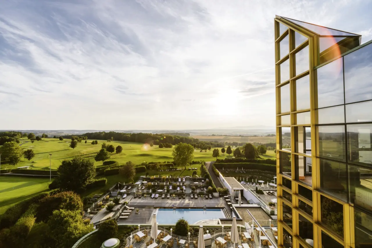 Panoramablick auf das moderne Hotel Reiters Supreme mit grossem Aussenpool, Sonnenterrasse und Golfplatz bei Sonnenuntergang.