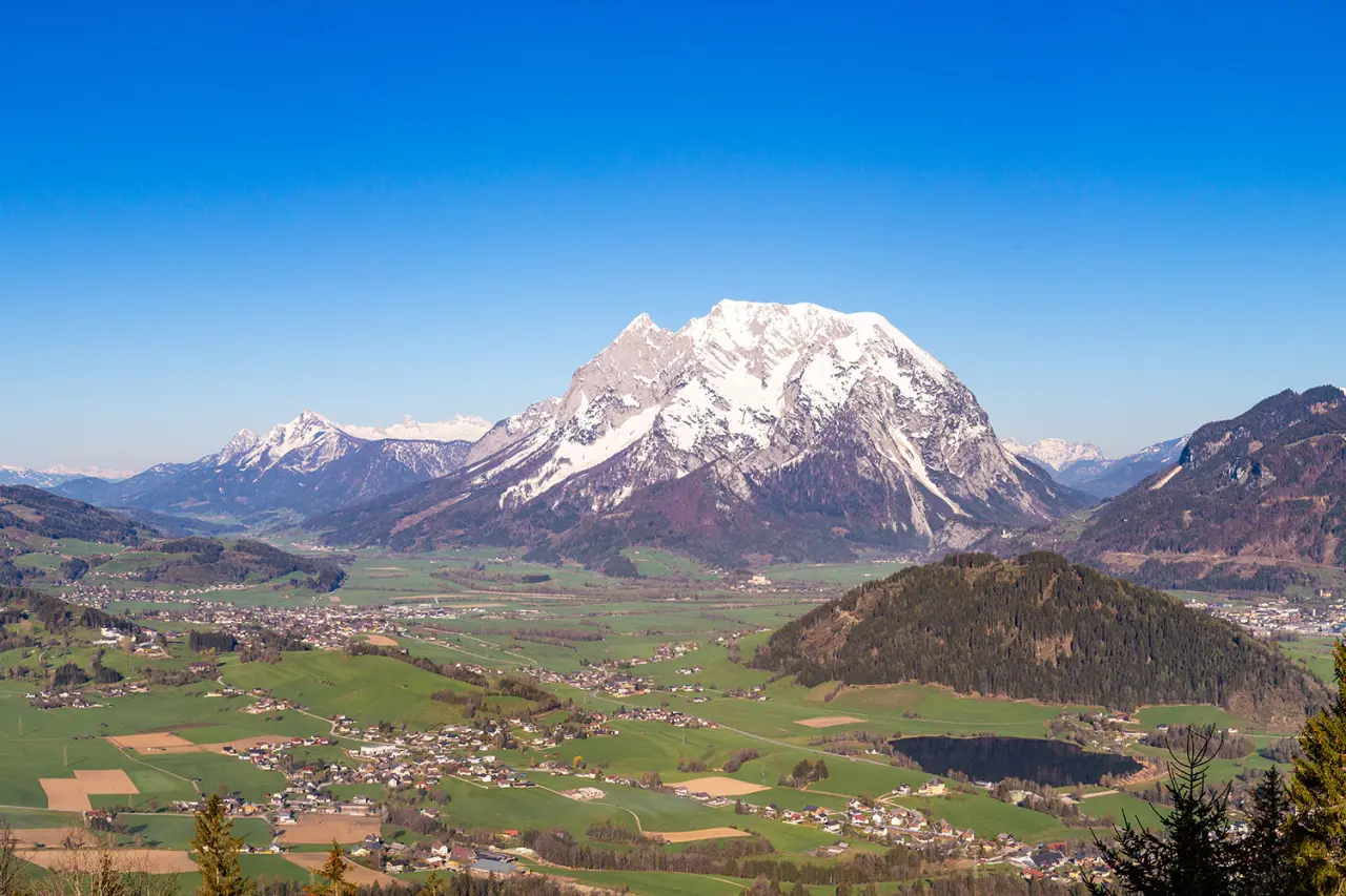 Bergpanorama mit schneebedecktem Gipfel, grünen Tälern und einem Dorf in der Umgebung des Hotel DER HECHL.
