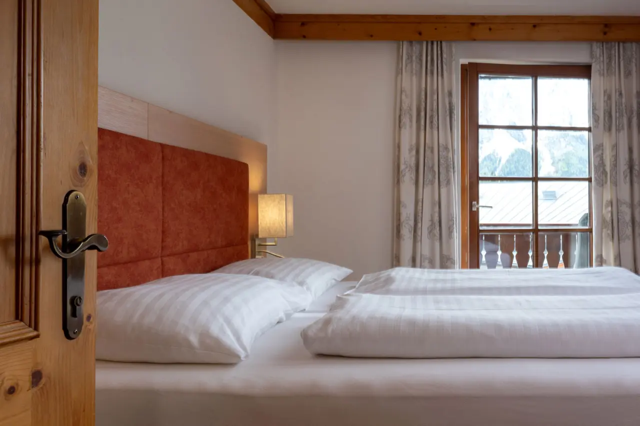 Gemütliches Doppelzimmer im Hotel DER HECHL mit bequemen Betten und Balkonblick auf die Berge.