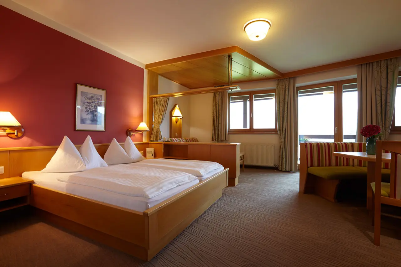 Gemütliches Doppelzimmer mit roter Akzentwand und Sitzbereich im Hotel DER HECHL.