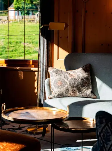 Gemütliche Sitzecke mit Kissen und Beistelltischen im Hotel Kesslermühle, mit Blick ins Grüne.