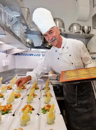 Lachender Koch des Hotel Kesslermühle bei der Zubereitung von Gourmet-Vorspeisen in der professionellen Küche.