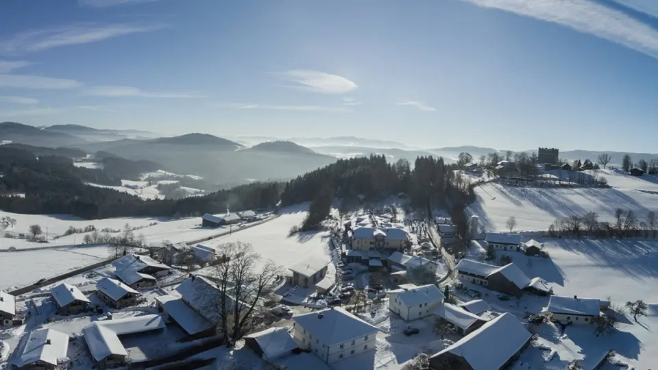 Winterliche Luftaufnahme vom Burghotel Sterr in verschneiter bayerischer Landschaft mit Burg und Bergen.