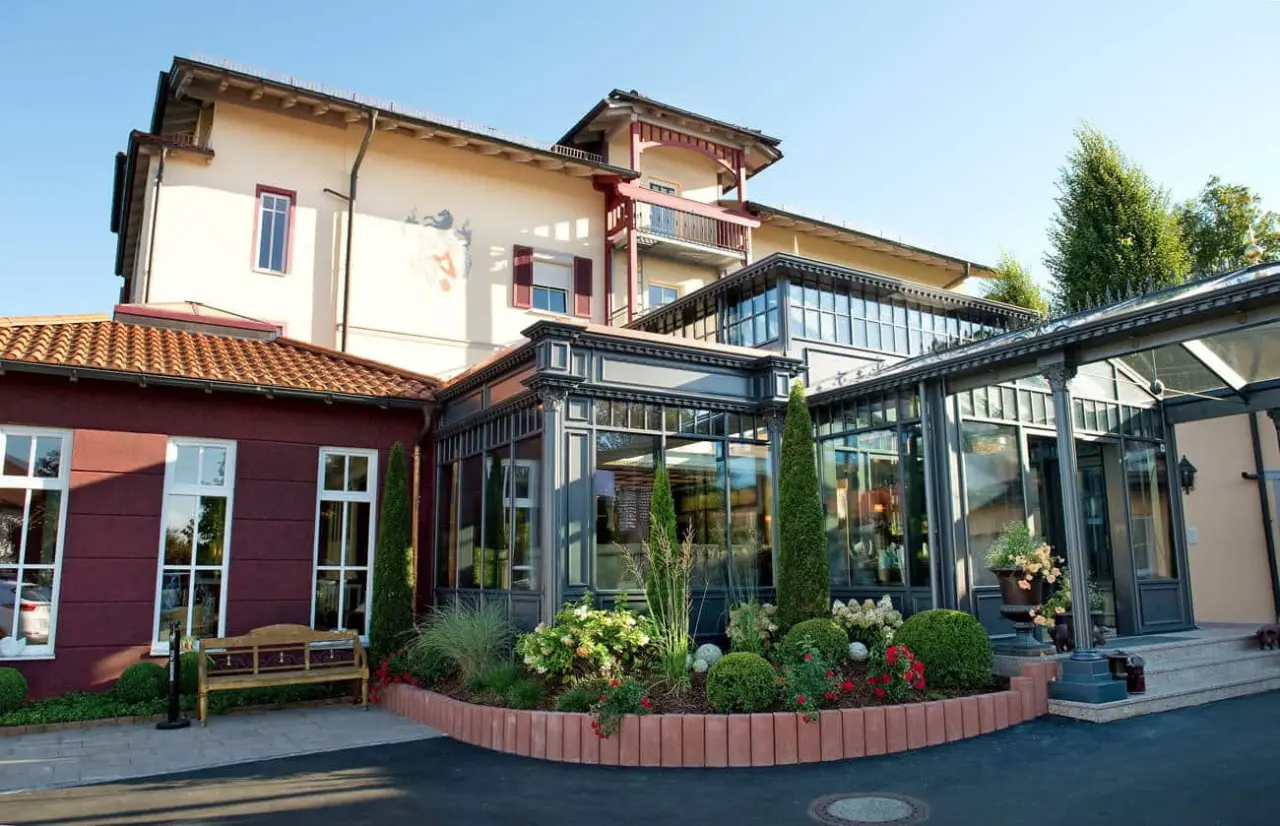 Aussenansicht des Burghotel Sterr mit hellem Gebäude, Wintergarten und gepflegtem Eingangsbereich.