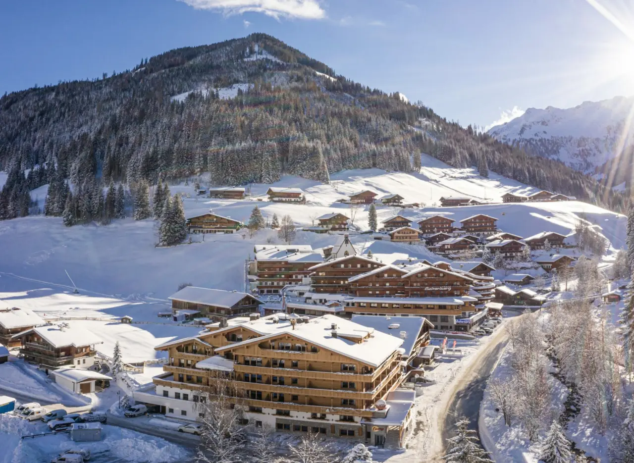 Winterliche Luftaufnahme des Galtenberg Resort in den verschneiten Alpen. Sonniger Tag mit Blick auf das Hotel und umliegende Berge.