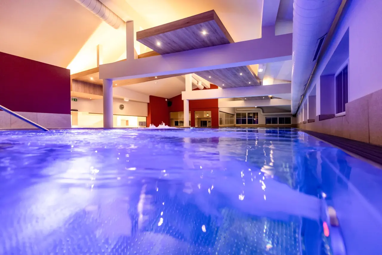 Modernes Hallenbad mit blauer Beleuchtung und architektonischen Details im Galtenberg Resort 4*S.