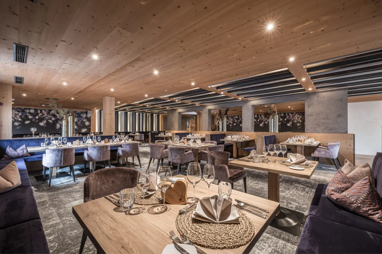 Elegantes Restaurant im Galtenberg Resort 4*S mit Holzakzenten, stilvoller Einrichtung und gedeckten Tischen.