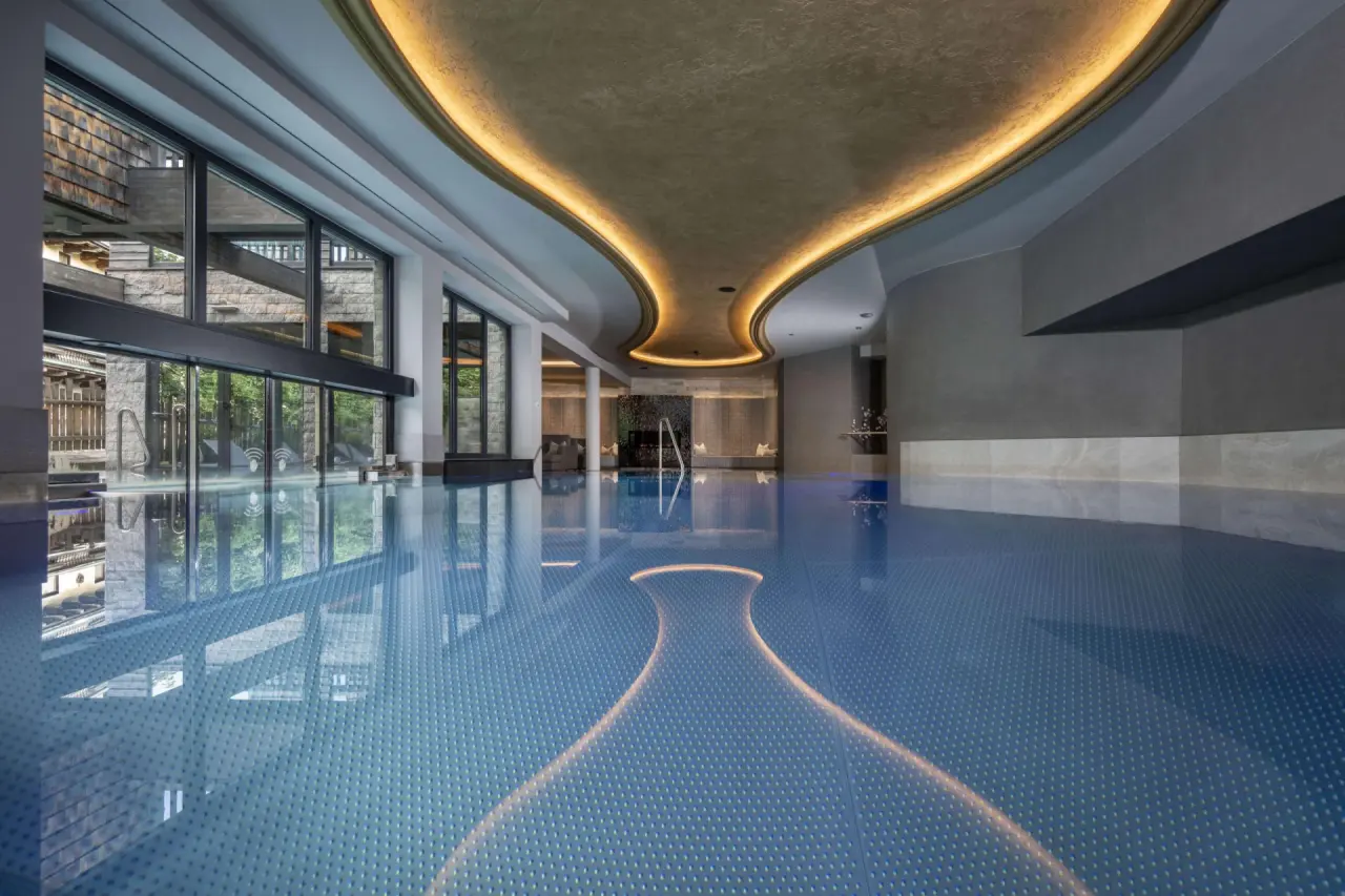 Grosszügiger Innenpool im Hotel Kendler mit elegantem Design, grossen Fenstern und stimmungsvoller Beleuchtung.