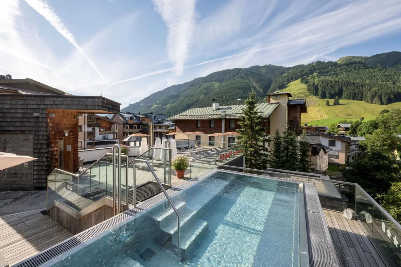 Beheizter Rooftop-Infinity-Pool mit Bergblick und Liegebereich im Hotel Kendler, umgeben von alpiner Landschaft.