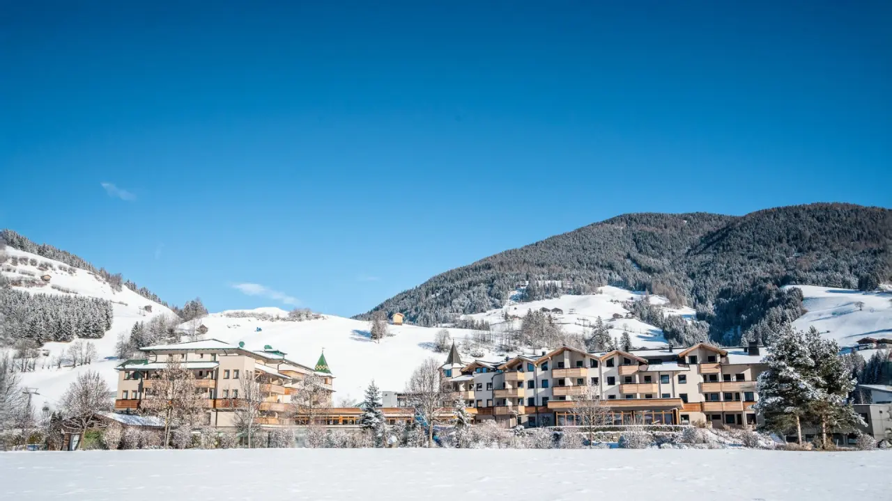 Dolomiten Residenz Sporthotel Sillian im Winter mit verschneiten Bergen und klarem blauen Himmel.