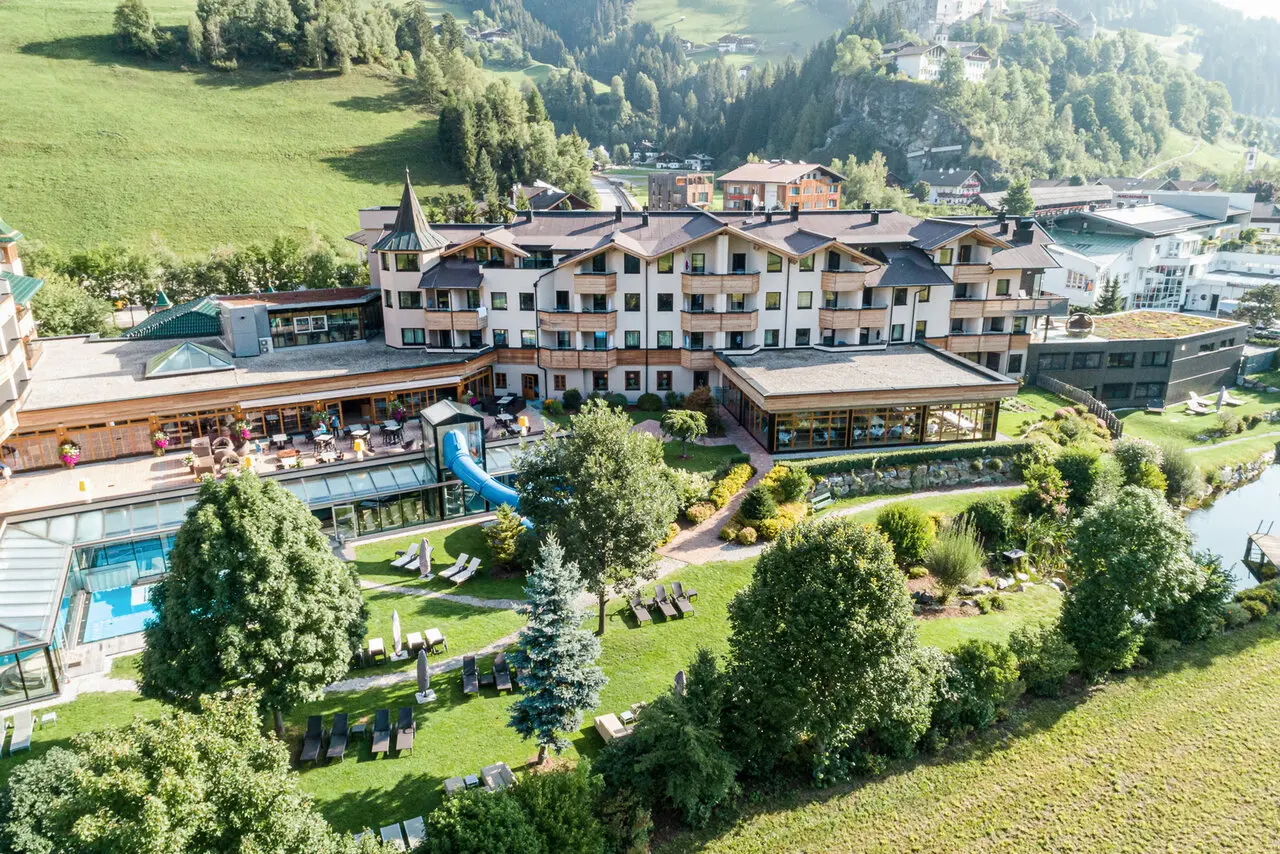 Luftaufnahme der Dolomiten Residenz Sporthotel Sillian mit Hotelgebäude, Poolbereich, Garten und umliegender Berglandschaft.