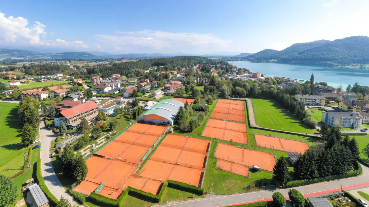 Luftaufnahme des Golf-Tennis-Wellnesshotel Mori: weitläufige Tennisplätze, Hotelgebäude und ein idyllischer See.