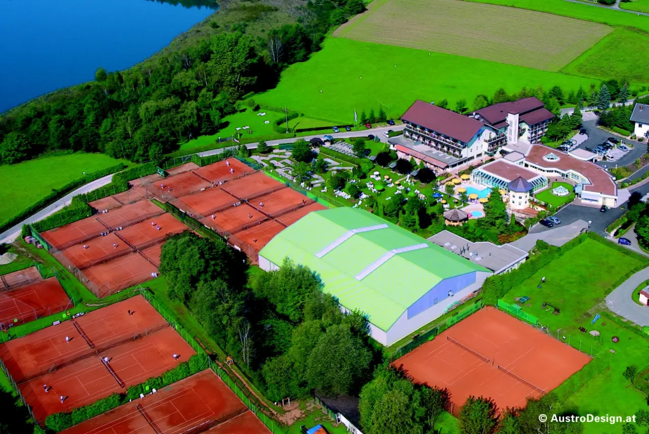 Luftbild vom Golf-Tennis-Wellnesshotel Mori mit See, zahlreichen Tennisplätzen, Poolbereich und weitläufiger Grünanlage.