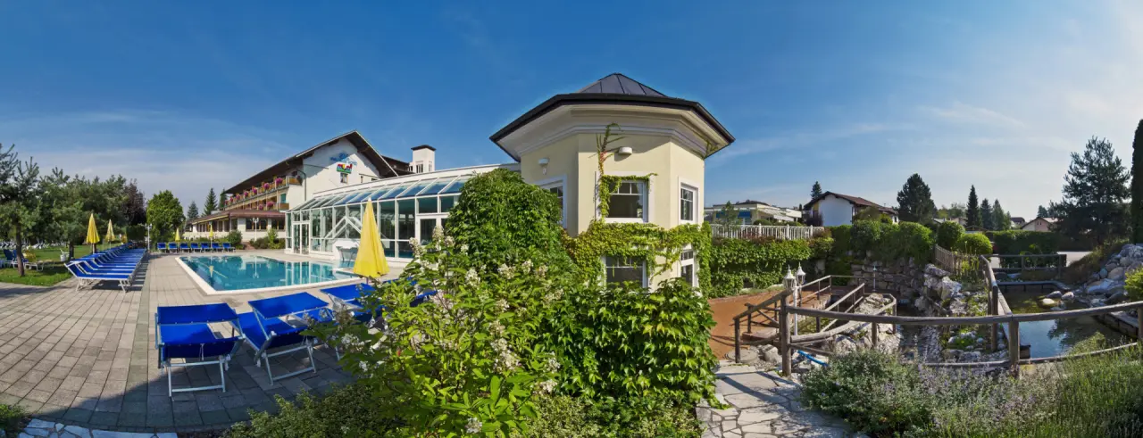 Aussenansicht des Golf-Tennis-Wellnesshotel Mori mit grossem Poolbereich, Sonnenterrasse und gepflegtem Garten.