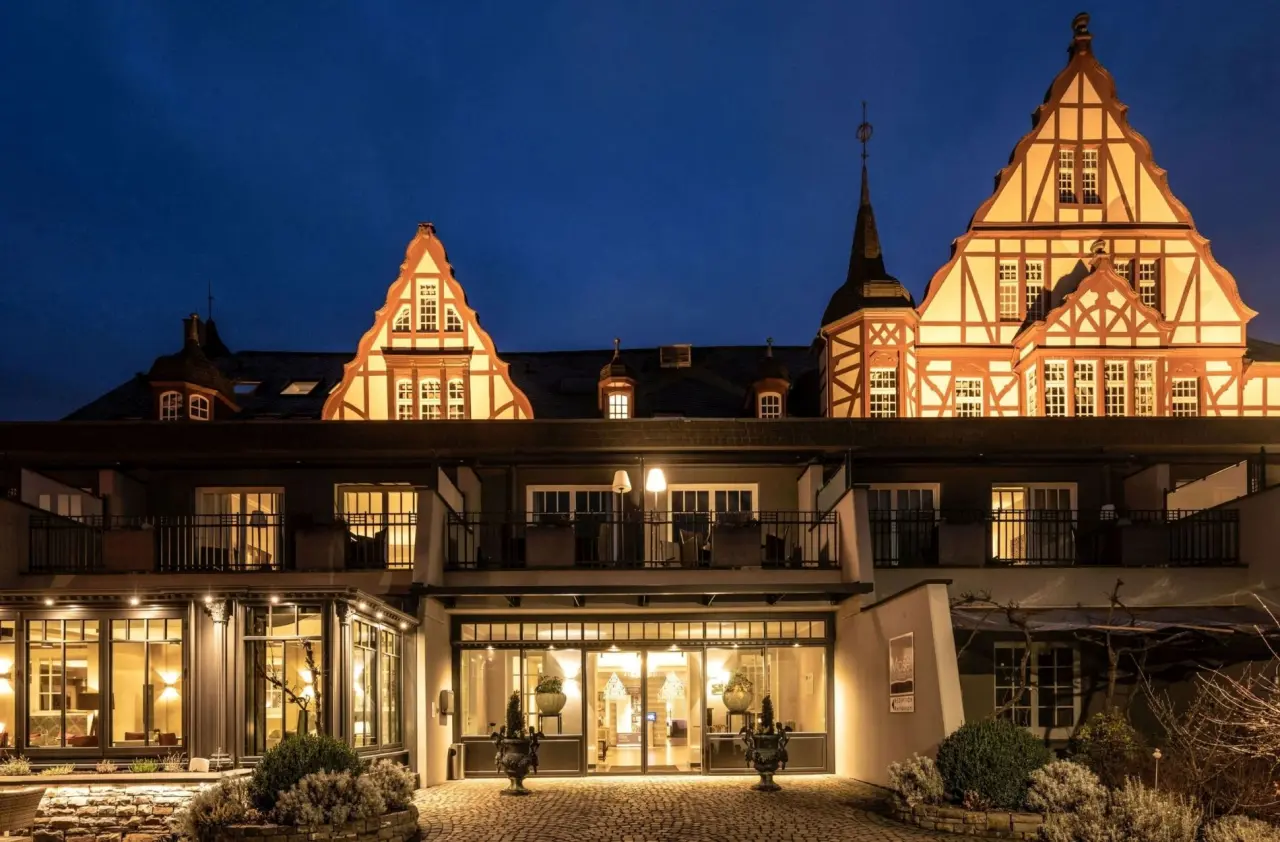 Abendansicht des historischen Moselschlösschen Spa & Resort mit beleuchteter Fachwerkfassade und Eingangsbereich.