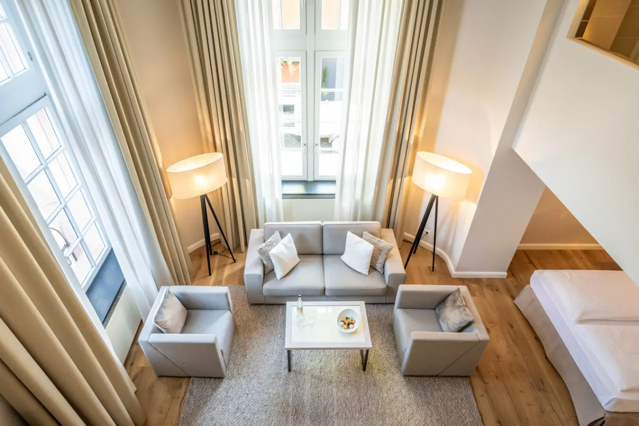 Geräumige Suite mit Wohnbereich und hohen Fenstern im Moselschlösschen Spa & Resort.