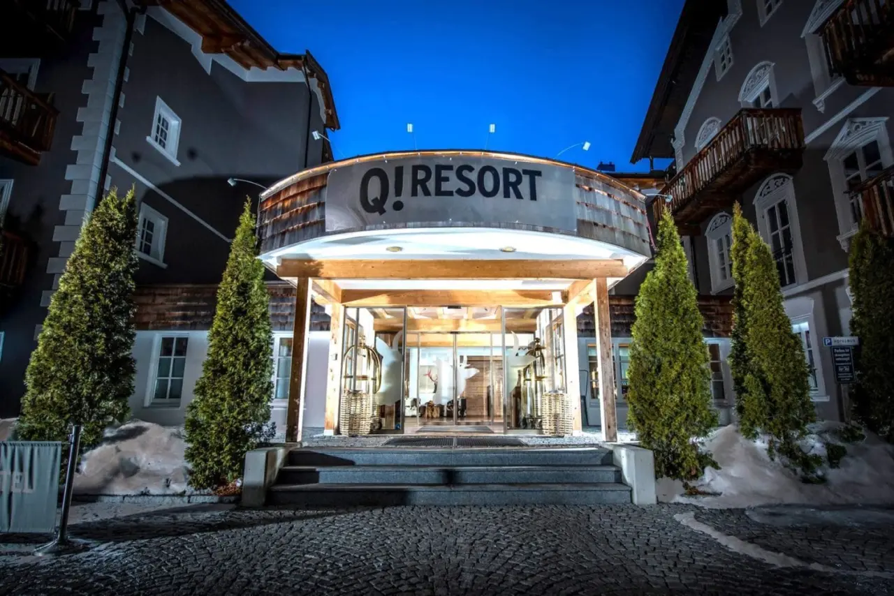 Beleuchteter Haupteingang des Q! Resort Maria Theresia Kitzbühel bei Nacht, mit alpiner Architektur und winterlicher Atmosphäre.
