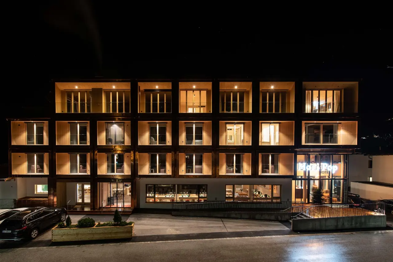 Moderne Aussenansicht des Mari Pop Hotels Zillertal bei Nacht mit beleuchteten Fenstern und warmem Licht.