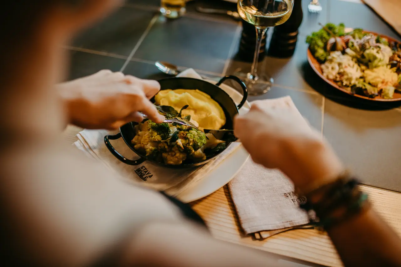 Gast genießt eine frische Mahlzeit mit Gemüse und Kartoffelpüree, dazu Weißwein, im Restaurant des Mari Pop Hotel Zillertal.