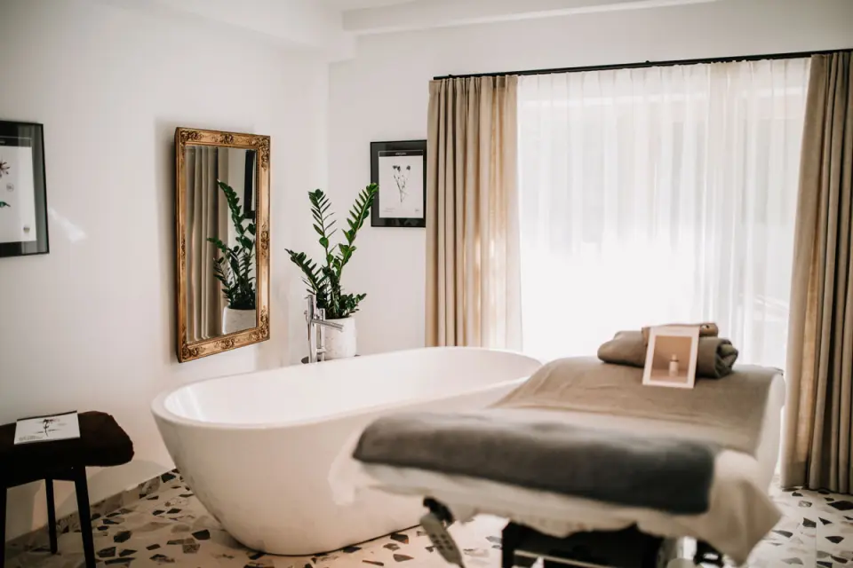 Freistehende Badewanne und Massageliege in einem hellen Spa-Raum im Mari Pop Hotel Zillertal.