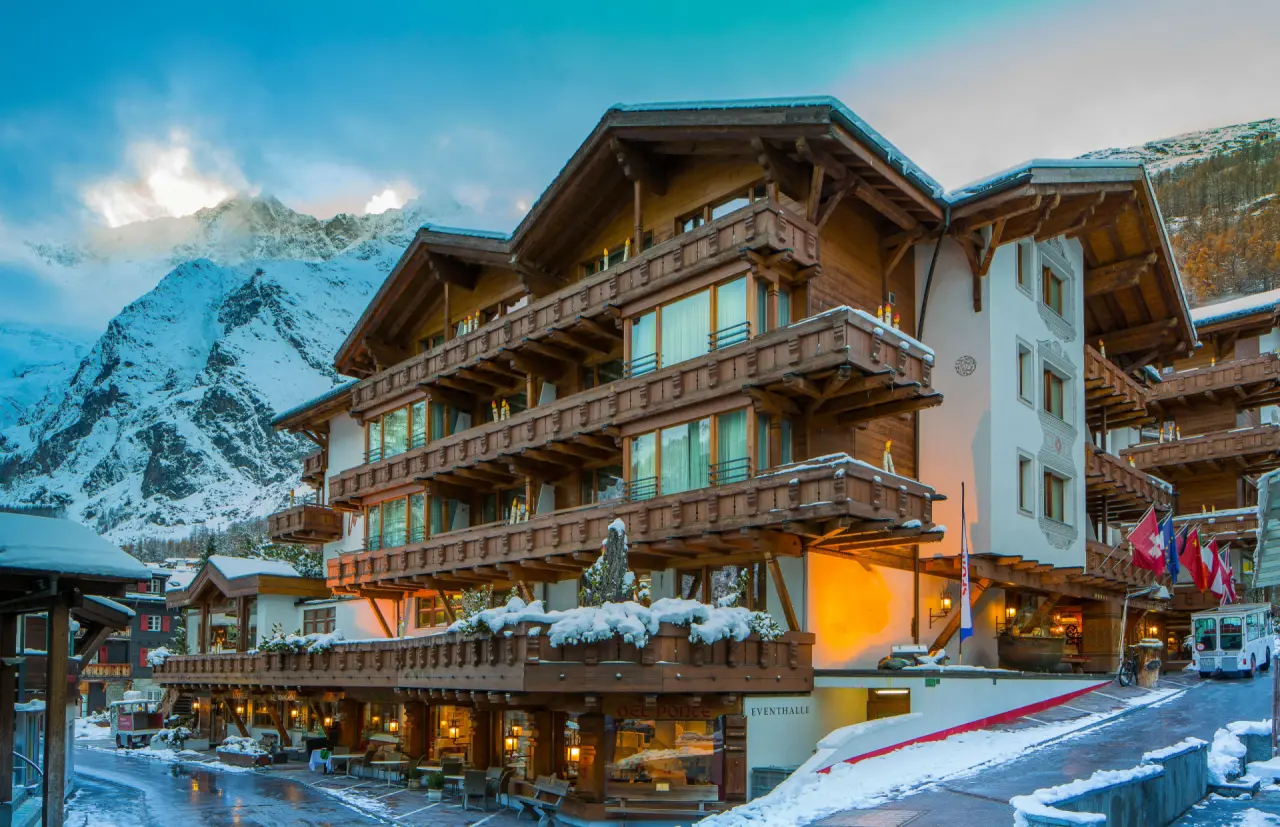 Majestätisches Walliserhof Grand-Hotel & Spa in Zermatt bei Dämmerung, umgeben von verschneiten Alpen.