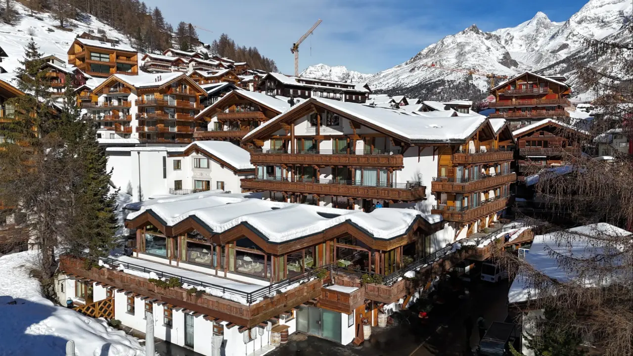 Winterliche Aussenansicht des Walliserhof Grand-Hotel & Spa in Saas-Fee mit verschneiten Dächern und Alpenpanorama.