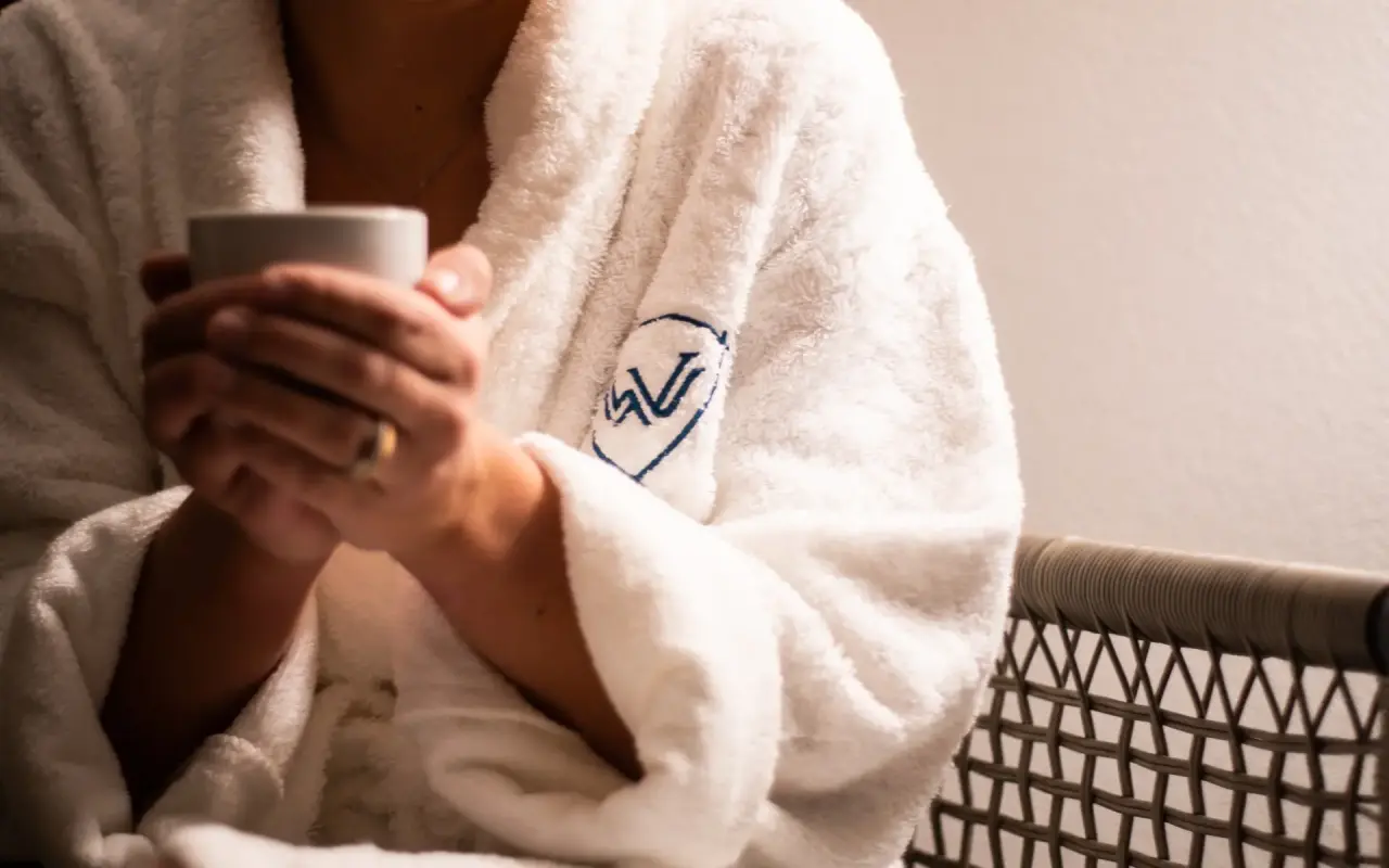Entspannung pur: Gast im Bademantel mit Walliserhof Grand-Hotel & Spa Logo genießt eine Auszeit.