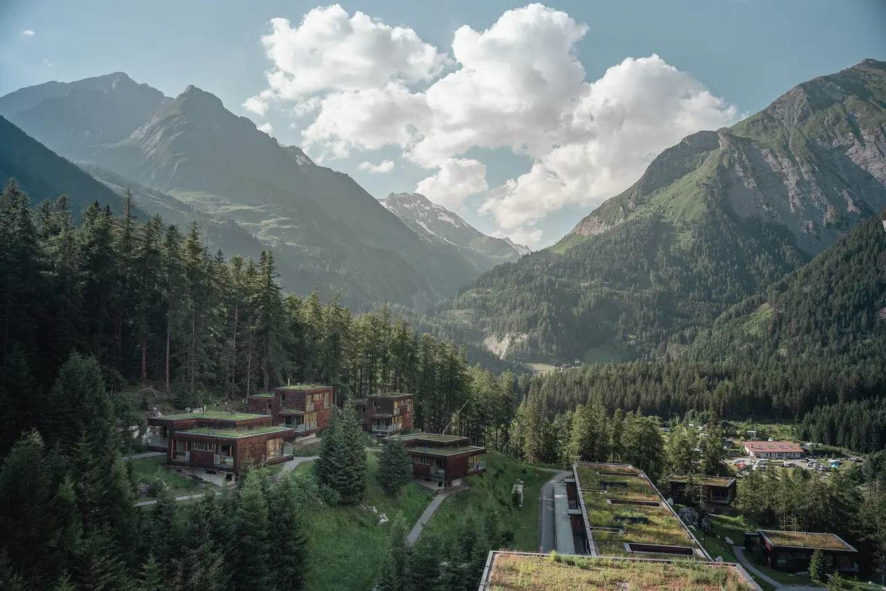 Panoramablick auf die modernen Chalets und das Hotel Gradonna****s Mountain Resort inmitten der alpinen Berglandschaft.