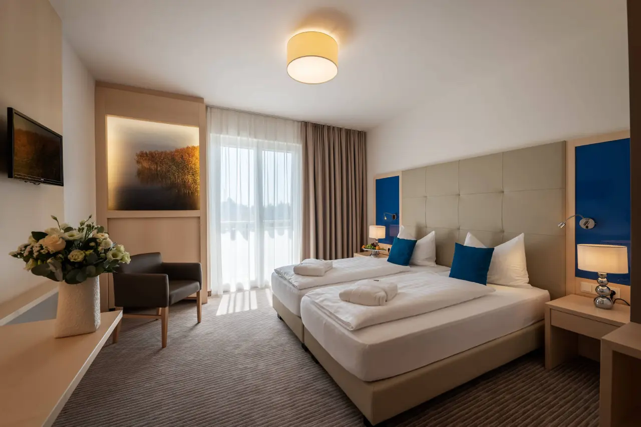 Komfortables Doppelzimmer im Hotel Wende mit Balkon, gemütlichem Sessel und moderner Einrichtung für entspannte Nächte.
