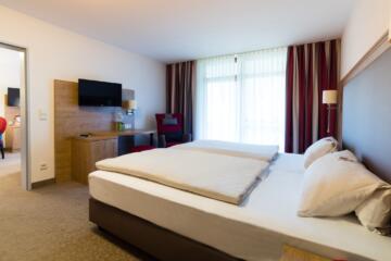 Helles Hotelzimmer mit Doppelbett, Schreibtisch und TV im Hotel St. Georg, einladend eingerichtet.
