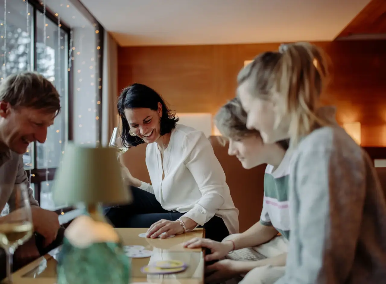 Familie spielt Gesellschaftsspiel und lacht in der gemütlichen Lounge des Familien- & Gartenhotel Theresia****S.