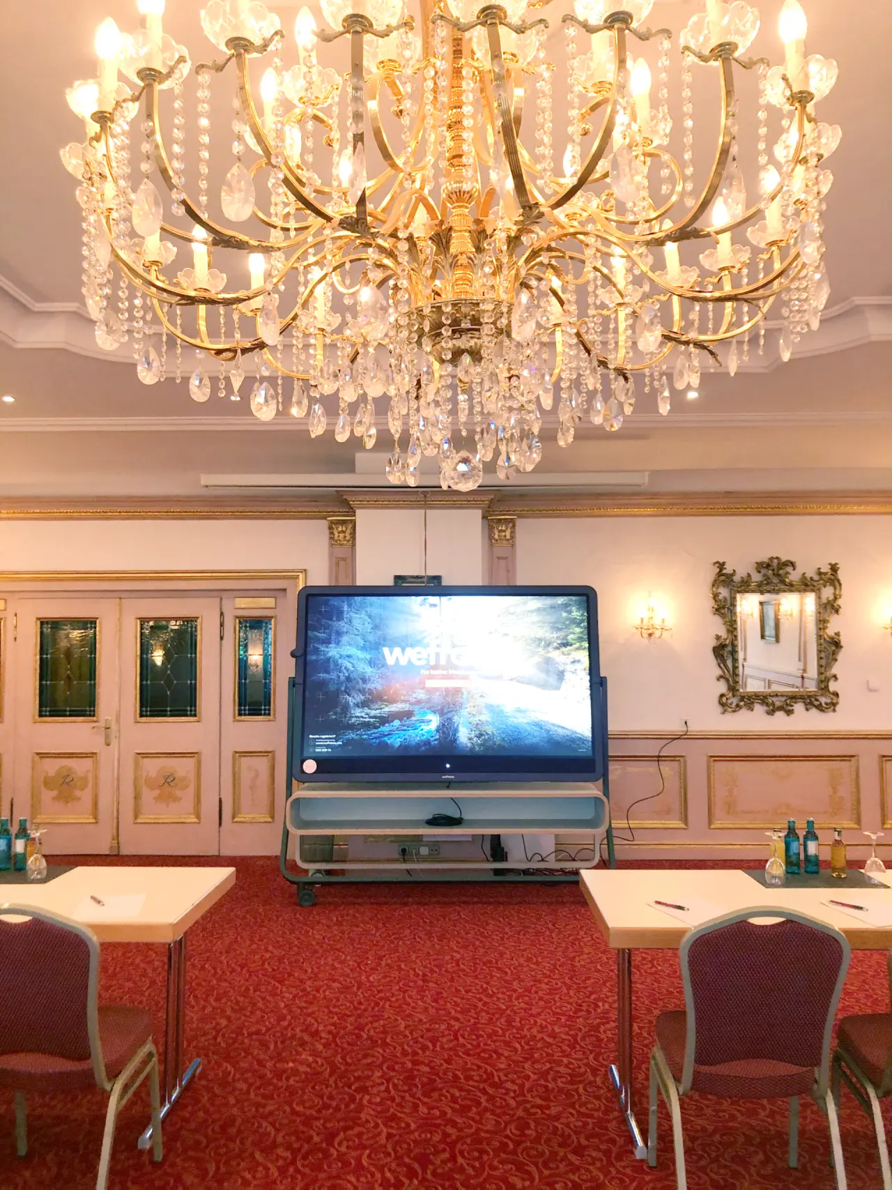 Konferenzraum mit Kronleuchter und grossem Bildschirm im Reiterhof Bellevue Spa Resort Wirsberg.