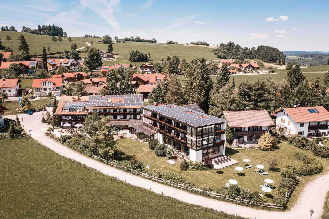 Luftaufnahme des Mittelburg Wellnesshotels mit moderner Architektur, Solaranlagen und grüner Hügellandschaft im Allgäu.