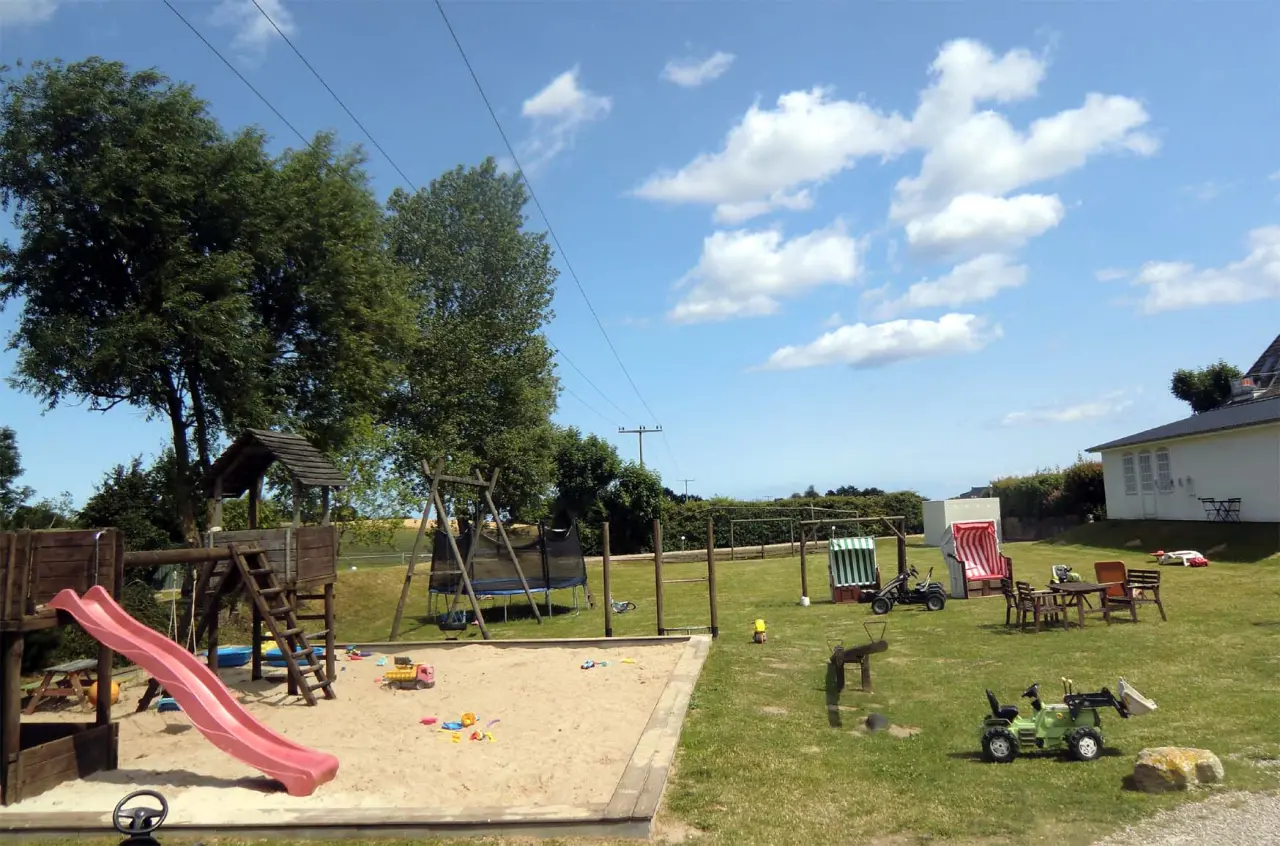 Spielplatz mit Rutsche, Sandkasten und Trampolin im Garten des HofHotel Krähenberg.