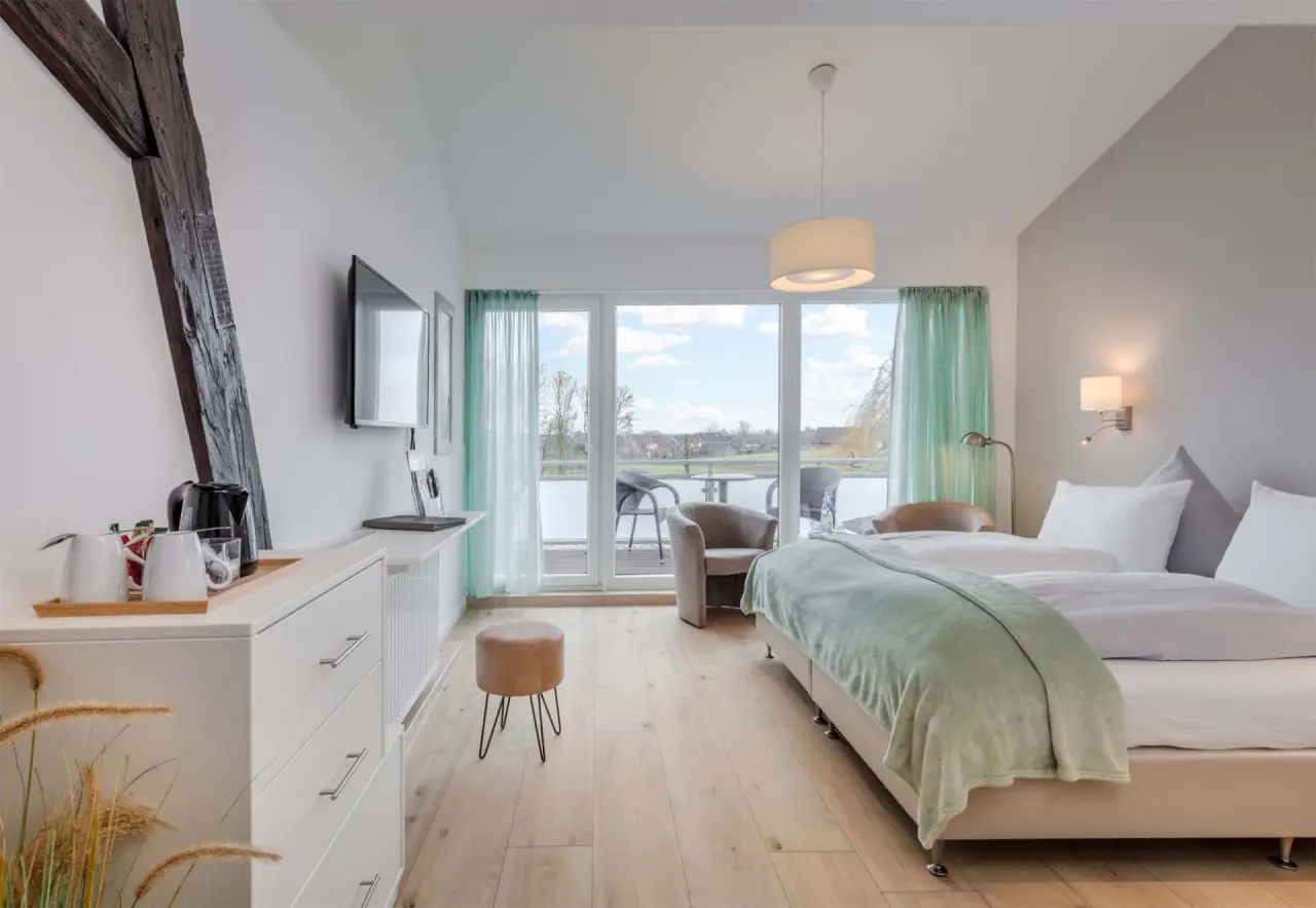 Helles und modernes Hotelzimmer im HofHotel Krähenberg mit Balkon, Doppelbett und Blick ins Grüne.