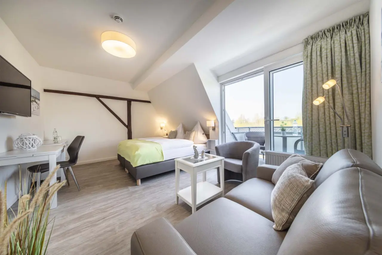 Geräumiges Hotelzimmer mit Doppelbett, Sofa, Schreibtisch und Balkon im HofHotel Krähenberg.
