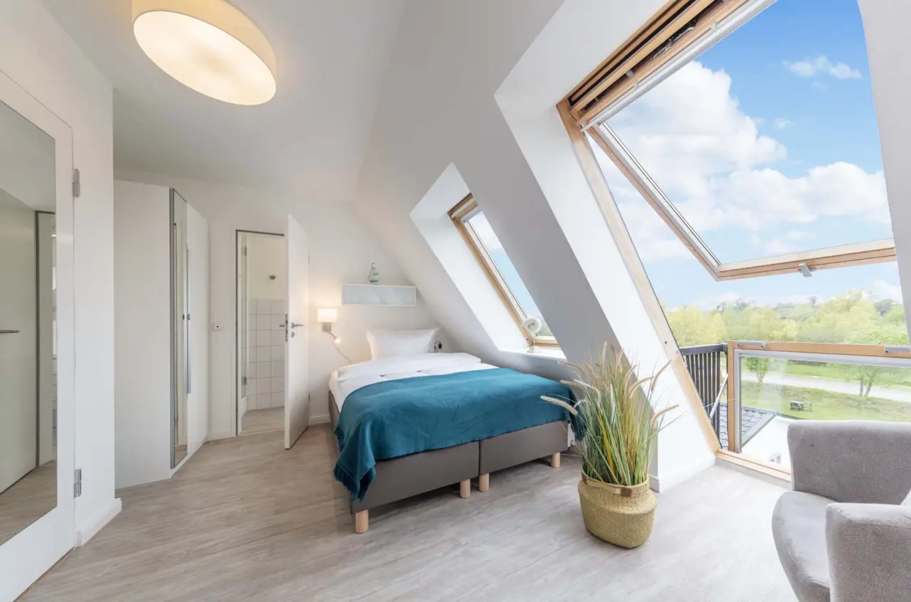 Helles Dachzimmer im HofHotel Krähenberg mit gemütlichem Bett, großen Dachfenstern und Blick ins Grüne.