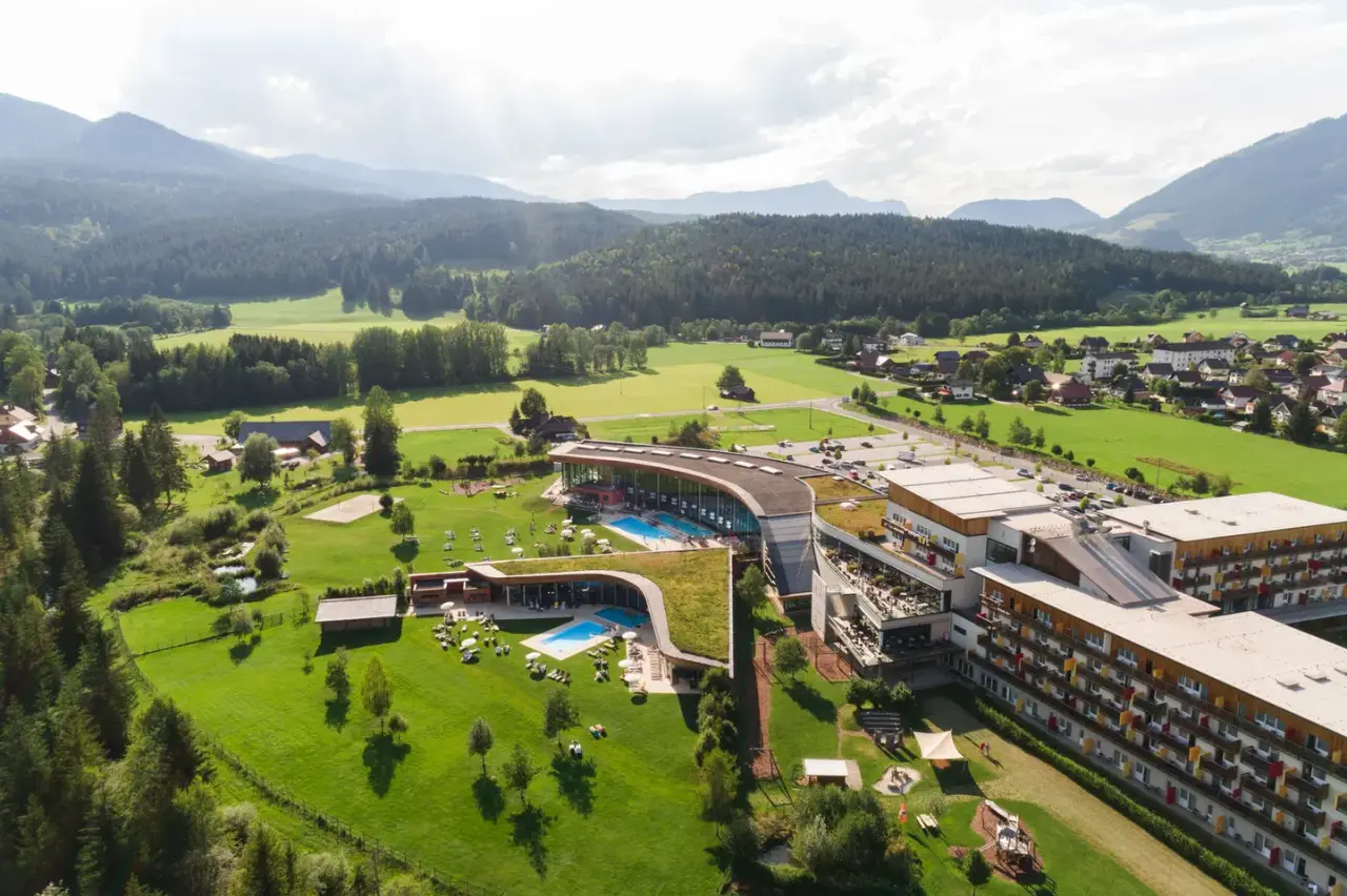 Luftaufnahme des Aldiana Club Salzkammergut mit Hotelanlage, Pools und grüner Landschaft vor Bergkulisse.