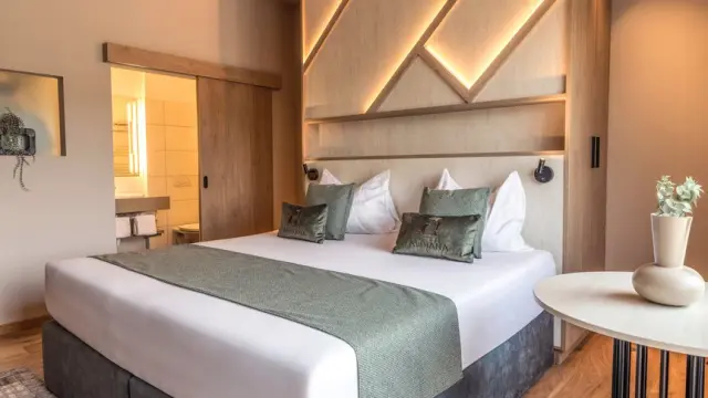 Modernes Doppelzimmer mit stilvollem Holzkopfteil und indirekter Beleuchtung im Aldiana Club Salzkammergut.