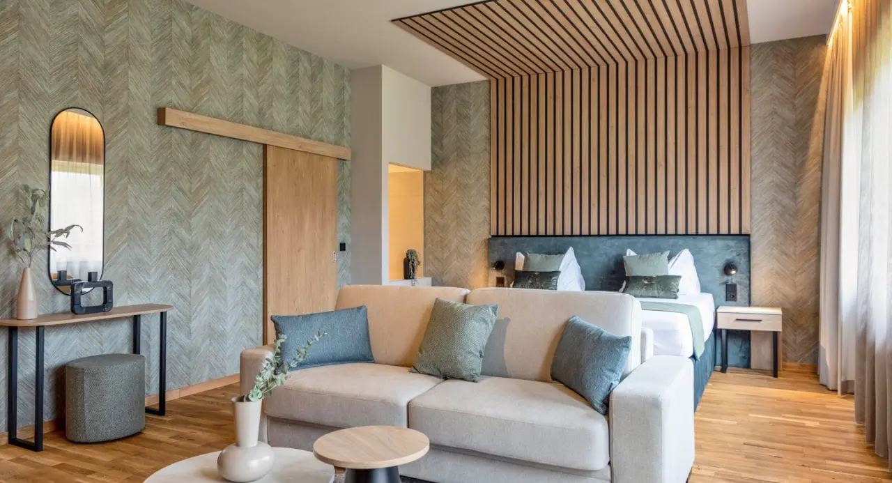 Modernes Hotelzimmer mit Sofa, Doppelbett und Holzelementen im Aldiana Club Salzkammergut.