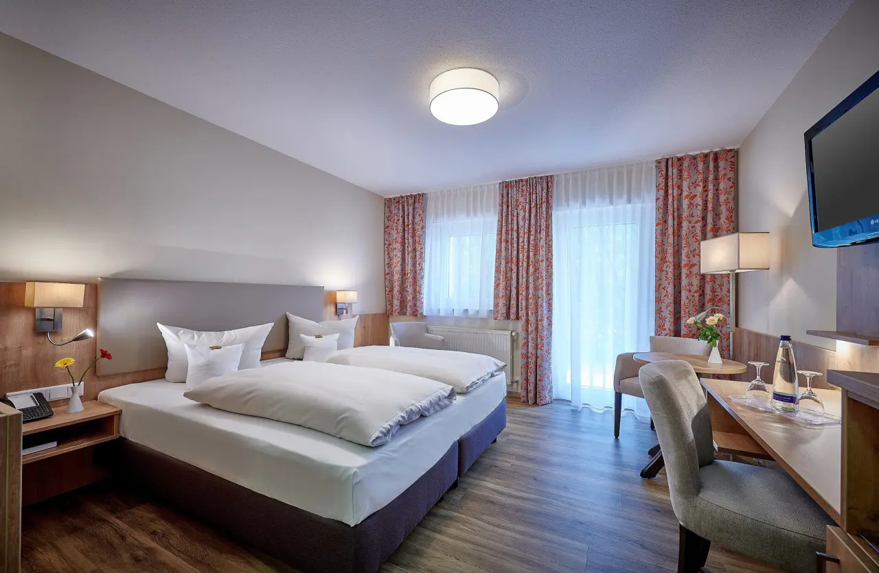 Komfortables Doppelzimmer im Hotel Herzog Heinrich mit gemütlichem Bett, Schreibtisch und Sitzbereich.