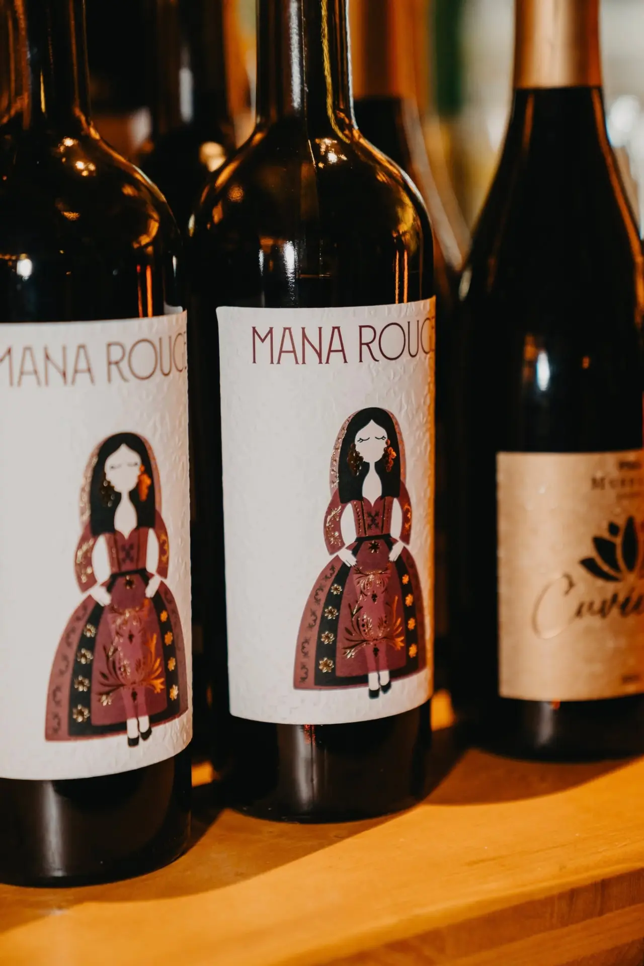 Nahaufnahme von Mana Rouge Weinflaschen mit kunstvollen Etiketten im Mana Lisa Boutiquehotel