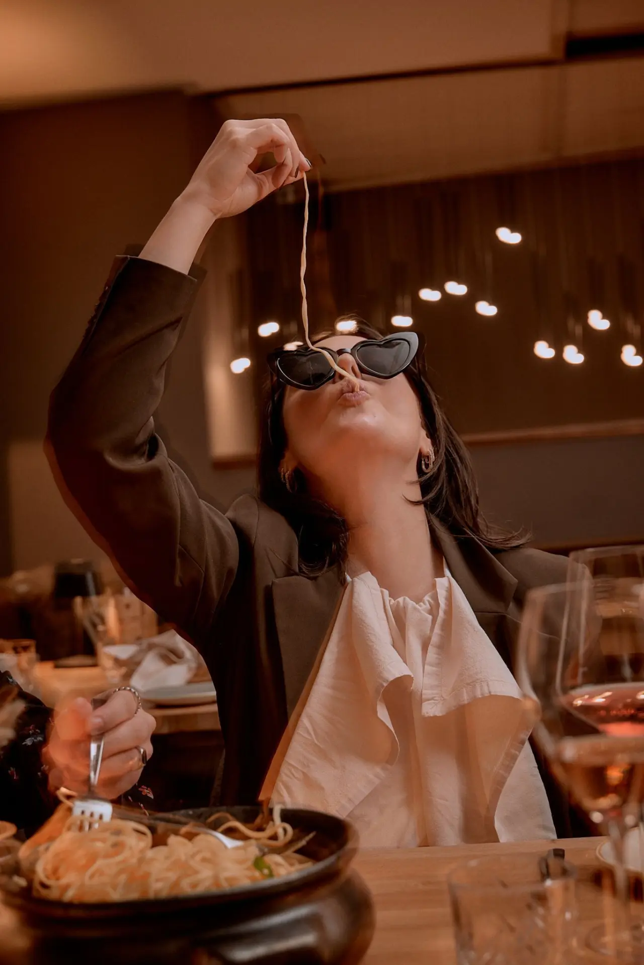 Junge Frau mit Herz-Sonnenbrille isst Pasta im stilvollen Restaurant des Mana Lisa Boutiquehotels.