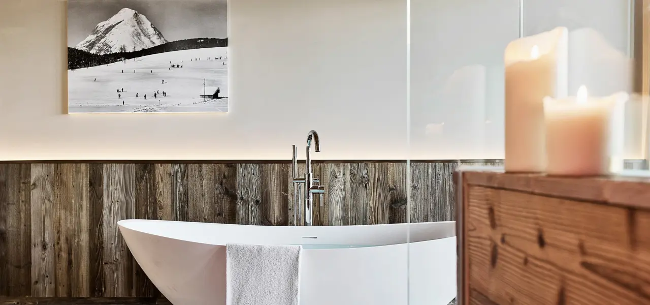 Moderne freistehende Badewanne mit Holzwand, Kerzen und Bergbild im Badezimmer des Natur & Spa Hotel Lärchenhof.