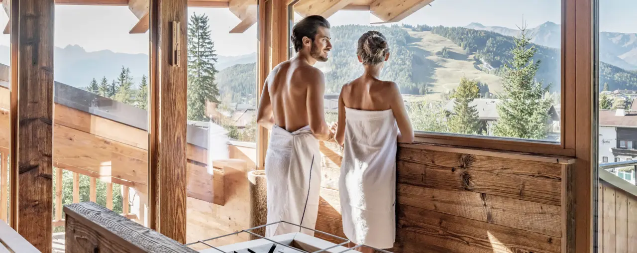 Paar in Bademänteln genießt den Bergblick aus dem Wellnessbereich des Natur & Spa Hotel Lärchenhof.