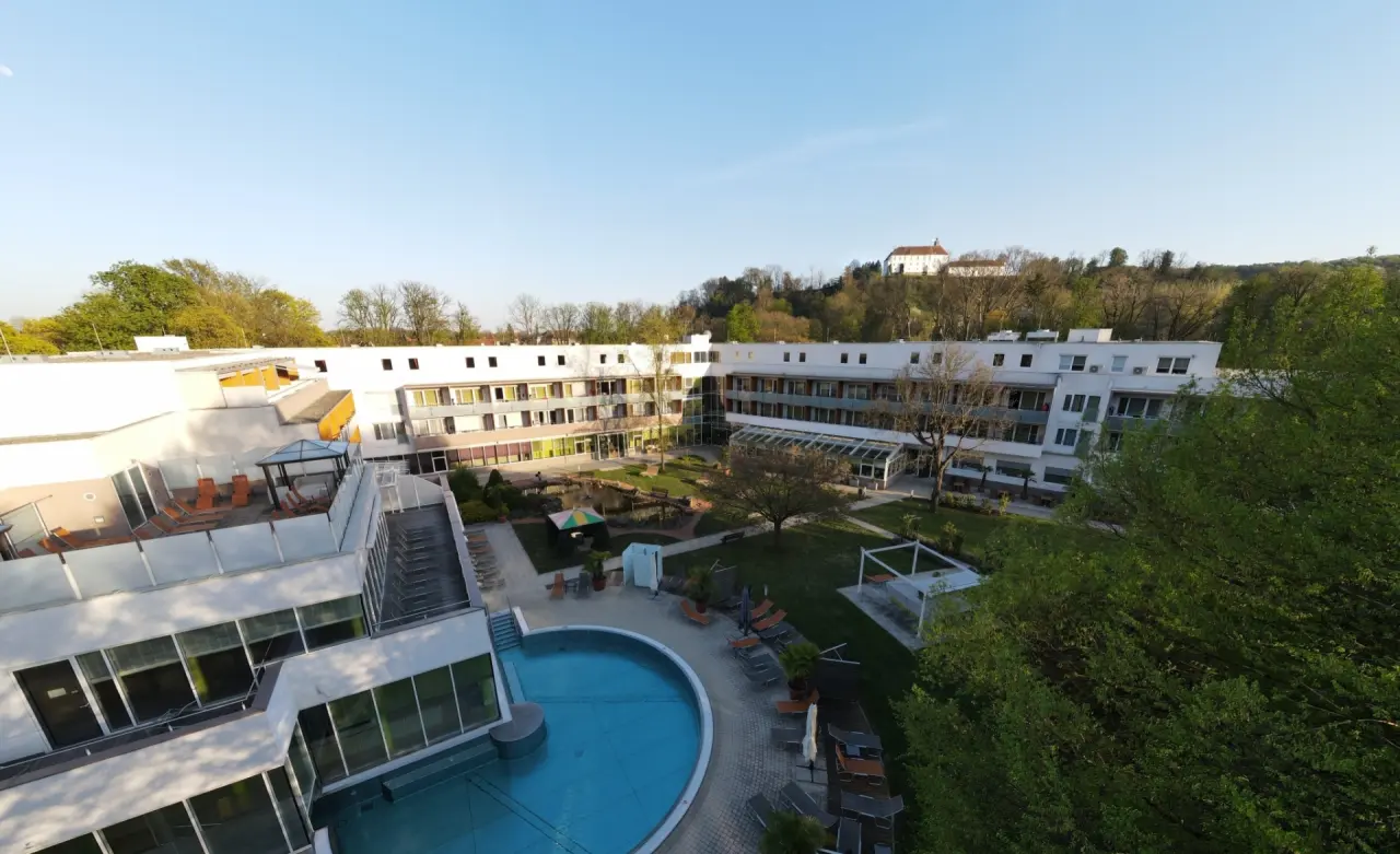 Thermalhotel Fontana: Gesamtansicht des Hotels mit Aussenpool, Gartenanlage und historischem Schloss im Hintergrund.
