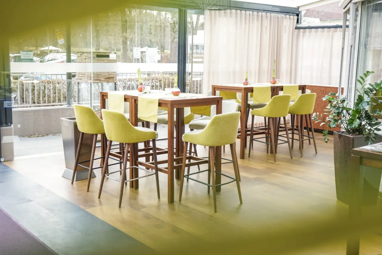 Gemütlicher Loungebereich mit hohen Tischen und grünen Barhockern im Thermalhotel Fontana.