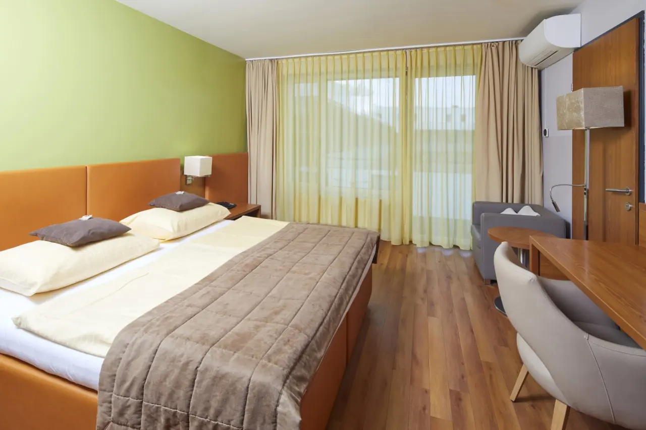 Modernes Doppelzimmer mit Holzboden, Doppelbett und Schreibtisch im Thermalhotel Fontana.